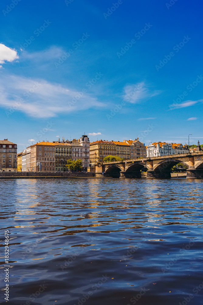 Naklejka premium Palacky Bridge. Boats cruising under historic stone bridge with buildings.