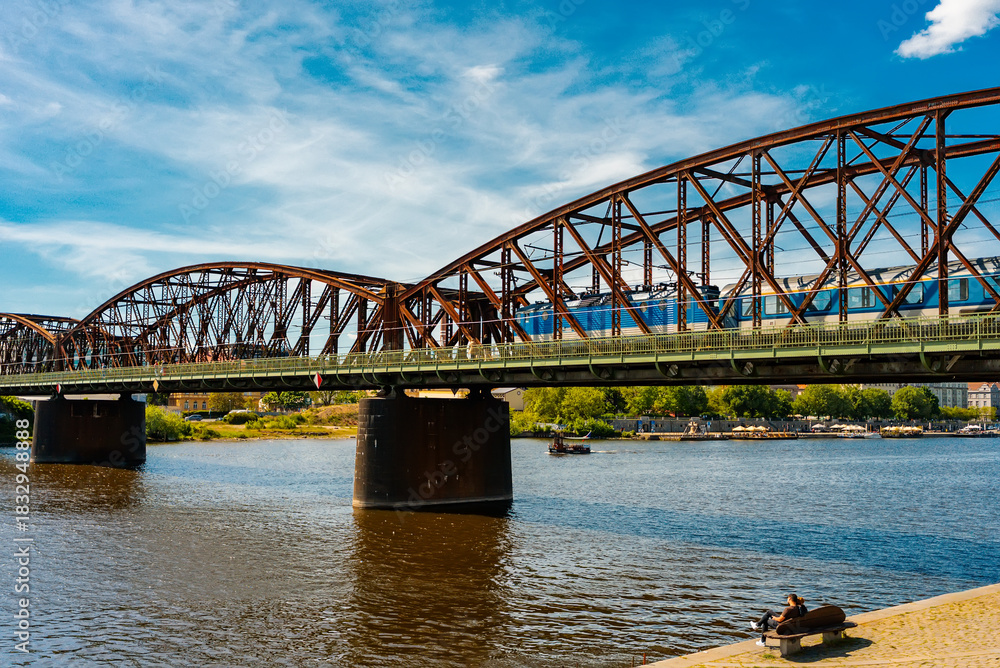 Naklejka premium Train crossing large metal arch railway bridge over river.