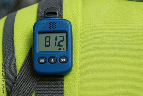 Blue sound level meter reads 81.2 dBA on safety vest during rubber manufacturing inspection with measured noisy environment and protective clothing