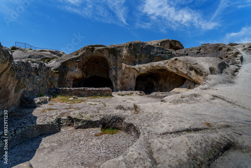 Cave dwellings carved in sandstone at Uplistsikhe under blue sky