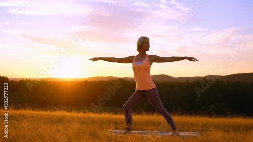 Woman performs yoga poses at sunset in a serene field
