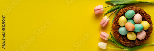 Easter nest filled with pastel colored eggs and tulips on yellow background