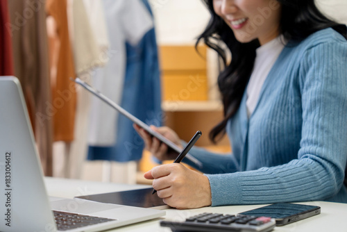 SME Startup : Small Business Entrepreneur. Asian female entrepreneur works in a clothing store. She checks the inventory of clothing in the store.
