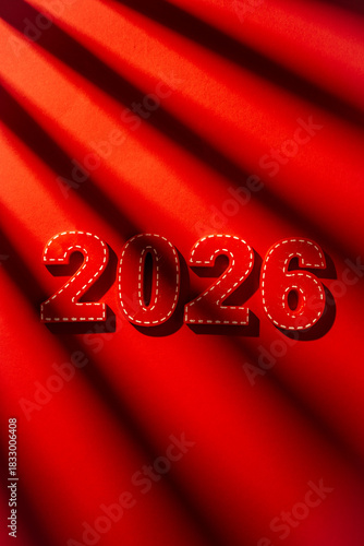 Red felt numbers forming 2026 with white stitching outlining each digit, creating a festive future concept for New year celebrations against a textured red background with dramatic light and shadow