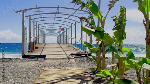he entrance to an exclusive VIP pier with cozy cabanas, where a wooden jetty extends far into the stormy sea with high waves and strong gusts of wind.
The video begins with the approach to the pier en
