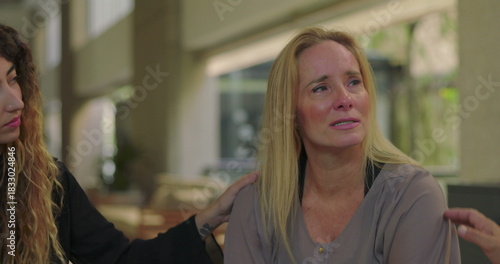 Woman consoled by fellow group members after emotional sharing, tearful moment of comfort and connection during healing group therapy session