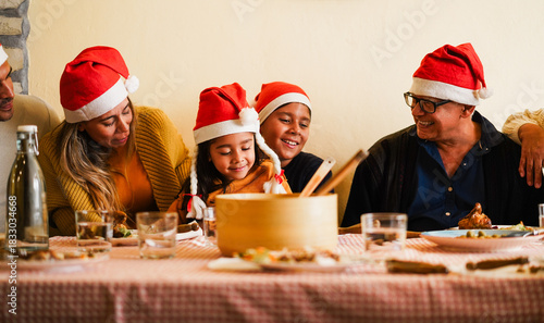 Happy latin family having fun eating together during Christmas time - Holiday concept - Soft focus on kid face