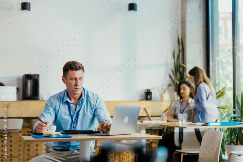 Young Professional Preparing for Meeting in Modern Office Cafe with Laptop and Notes