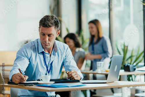 Young Professional Preparing for Meeting in Modern Office Cafe with Laptop and Notes