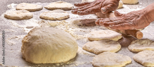 Old woman hands hands keep rolling pin with flour on table. Woman rolling out dough on kitchen table, closeup