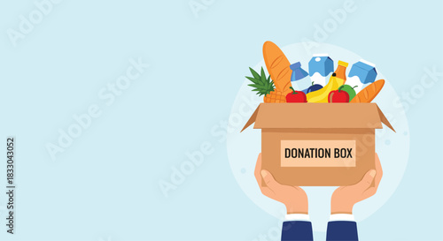 Two hands holding up a cardboard donation box full of fresh food and groceries for a charity drive or humanitarian aid project.