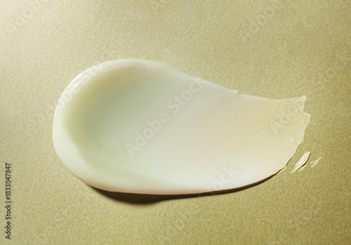 Smudge of thick yellow cream on metallic background. Beauty product sample swatch