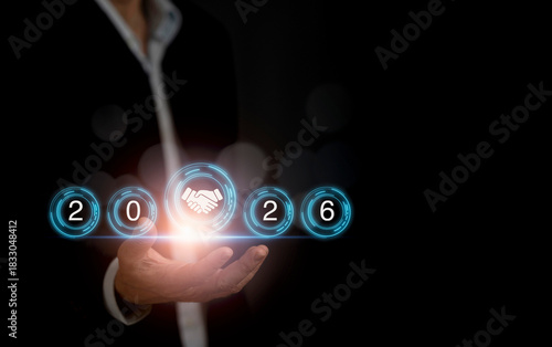 Business professional holding a 2026 handshake icon, symbolizing new goals and partnerships for the new year.