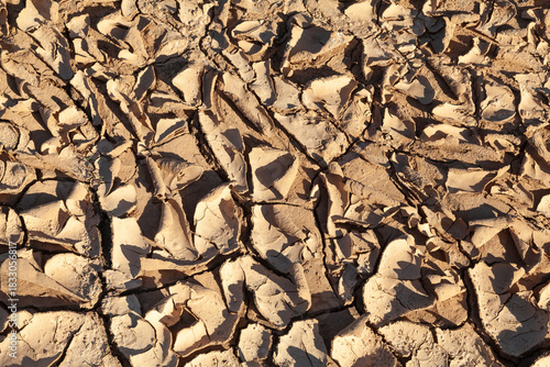 Dried flaking mud texture in the bottom of an empty reservoir during a drought, environmental issues, climate change, extreme weather, natural disaster