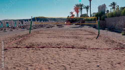 An empty volleyball court on a resort beach comes alive in the breeze, where the net gently sways, creating an atmosphere of tranquil anticipation