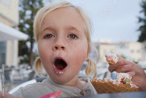 Girl eating ice cream and looking surprised at camera