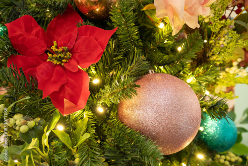A lush Christmas tree adorned with poinsettia blooms, glittering ornaments, and twinkling lights creates a warm, seasonal centerpiece for holiday celebrations and cozy home decor.