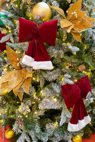 A lush Christmas tree adorned with red velvet bows, golden ornaments, and warm twinkling lights.