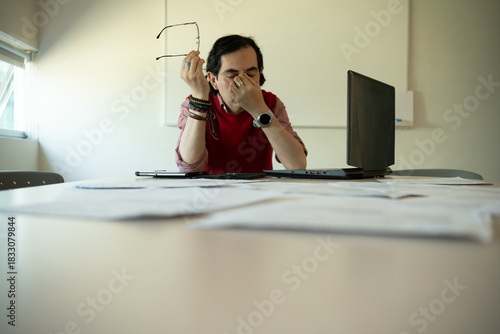 Exhausted Teacher Grading Student Papers at Her Desk, Overwhelmed Educator With Stack of Homework to Grade
