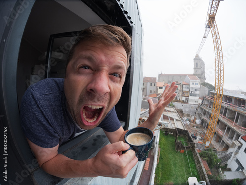 Angry man looking out the window with coffee