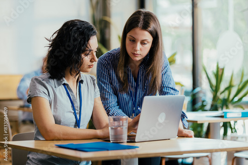 Two Female Startup Team Members Preparing Pitch Presentation Notes at Conference Venue Cafe
