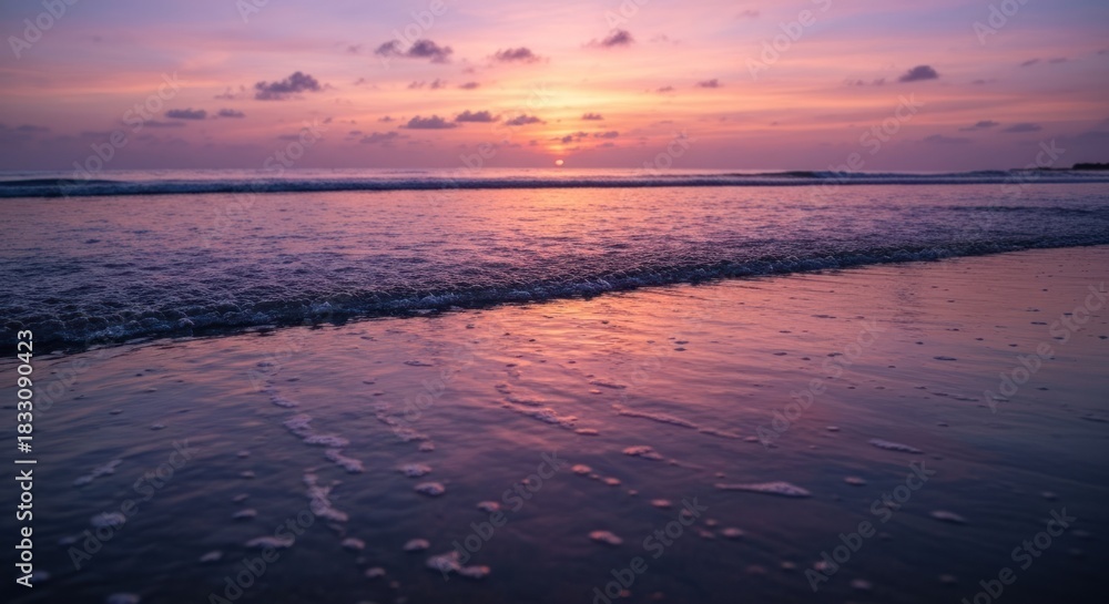 Fototapeta premium Vibrant sunset over a tranquil beach. Gentle waves lap at the shore, reflecting the fiery hues of the sky