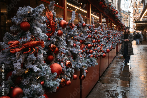 Christmans decorations adorn the streets as a person walks through a festive market on a rainy day.