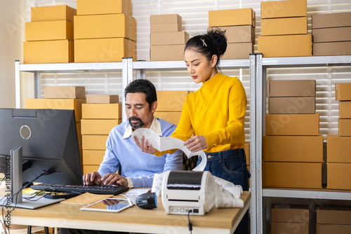 Working couple managing online orders in small business warehouse, reviewing shipping labels, updating inventory details, coordinating daily logistics workflow, busy e-commerce technology operation
