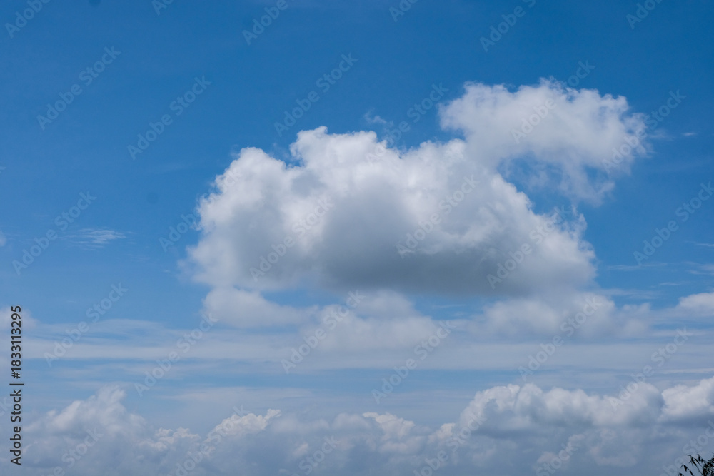 Naklejka premium A soft, fluffy white cloud floating against a clear blue sky, creating a calm and minimal natural scene.