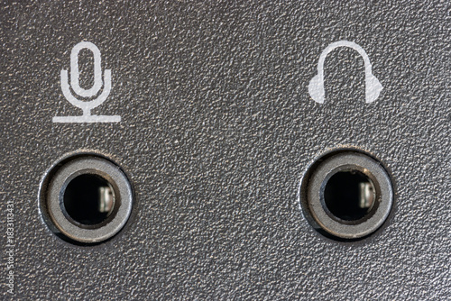Close-up of two audio jacks - microphone and headphones set into a black textured panel.