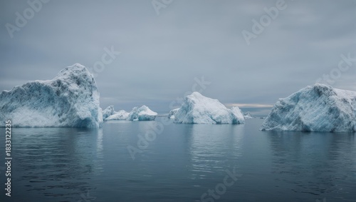 Majestic Icebergs Floating in Calm Arctic Waters Under a Cloudy Sky.