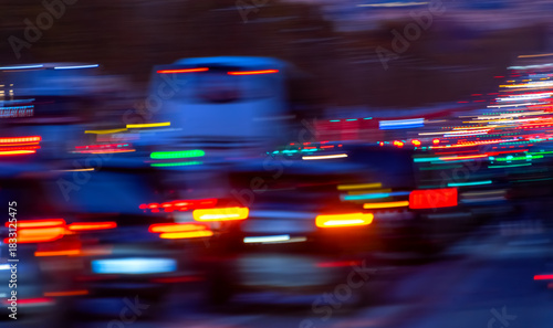 Fototapeta Naklejka Na Ścianę i Meble -  Busy main street in Paris with many blurred colorful lights from passing cars. Boulevard in the French capital at dusk or blue hour. Rush hour with traffic jam on the 