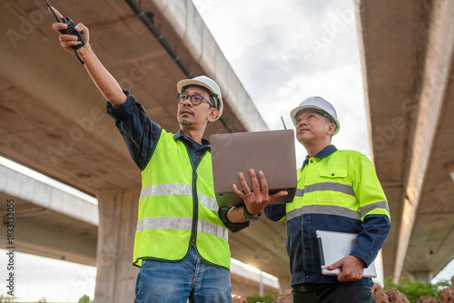 Construction workers coordinating safety measures under elevated highway urban environment action scene