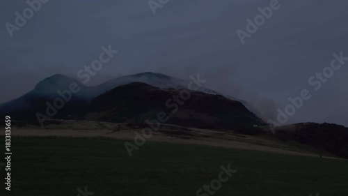 EDINBURGH, SCOTLAND, UK - AUGUST 10, 2025: Fire is seen on Arthur's Seat, a prominent hill in Holyrood Park, the blaze is occurring during the evening.