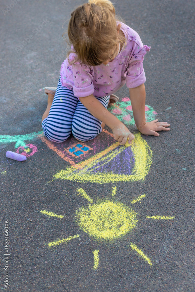 Fototapeta premium Children drawing with chalk on the asphalt. Selective focus.