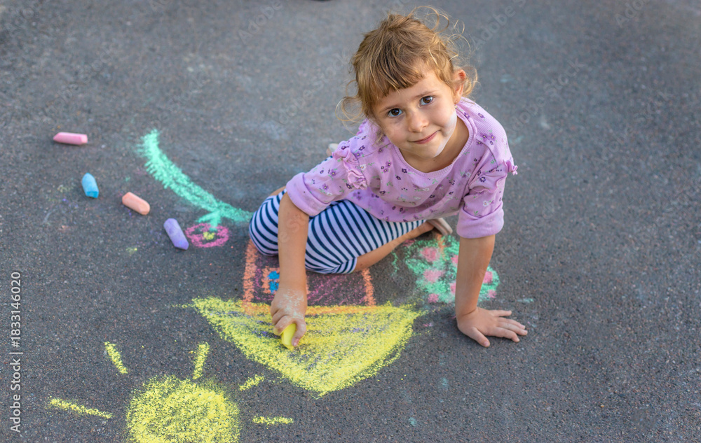 Naklejka premium Children drawing with chalk on the asphalt. Selective focus.