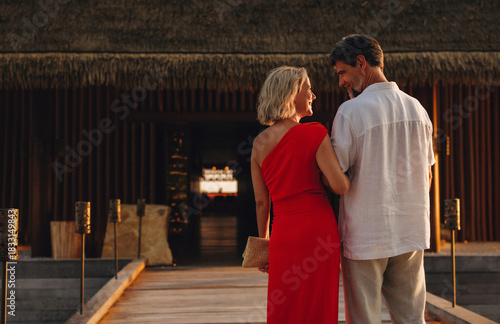 Romantic couple walking to luxury resort restaurant at sunset on honeymoon