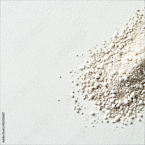 A close-up shot of a pile of white powder on a textured white surface. The composition is minimalist, with bright lighting.