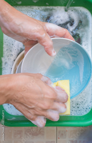 woman washing dishes in the kitchen, closeup of hands with sponge