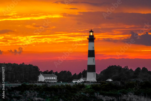 The historic Bodie Island Lighthouse, with its black and white stripes, is backed by a colorful sunset sky in Cape Hatteras National Seashore on the North Carolina Outer Banks.