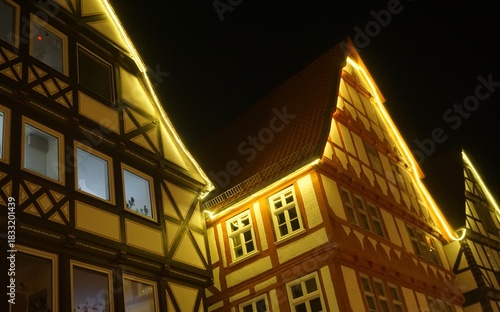Weihnachtsdekoration mit Lichterketten an Dächern von alten hohen Fachwerkhäusern in Altstadt vor schwarzem Himmel bei Frost und Kälte in der Nacht im Winter