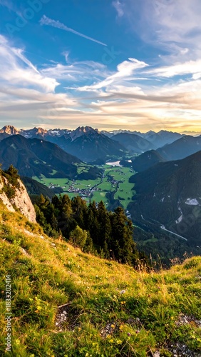 Breathtaking mountain valley view with grassy slope and a golden sky at sunset