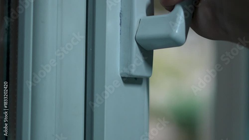 Man opens a white plastic window at home