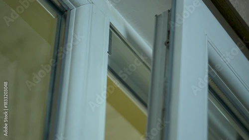 Man opens a white plastic window at home