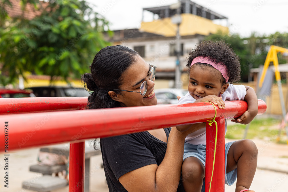 Obraz premium Young Latina Brazilian mother playing in the park with her black daughter. Rio de Janeiro, Brazil.