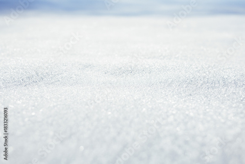 Close-up of sparkling, granular snow or frost texture. Shallow depth of field creates a bright, pure, and clean winter background with soft blue tones. Holidays Christmas day
