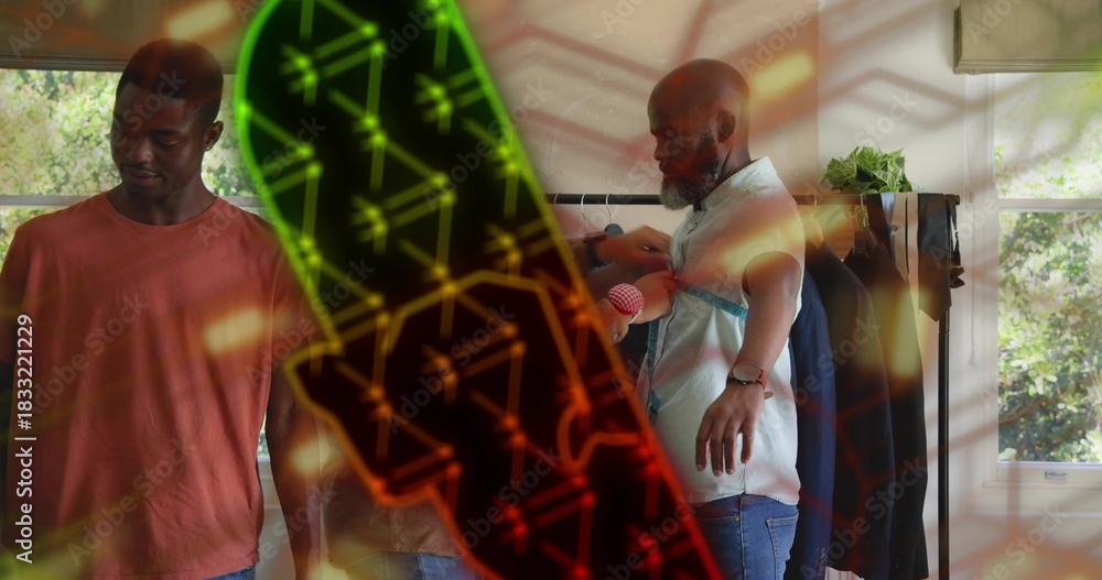 Obraz premium Stylist adjusting light button-up on mature man at boutique, clothing rail and plant visible
