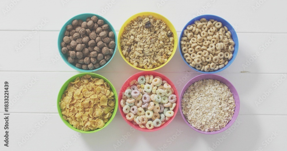 Fototapeta premium Displaying six colorful bowls sitting in neat 2x3 grid on white painted wooden tabletop, cereals