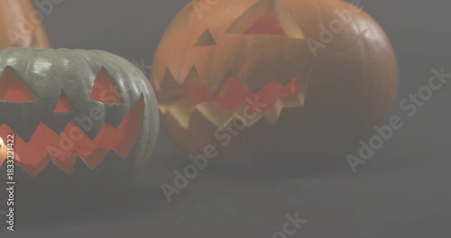 Glowing carved pumpkins sitting on dark studio tabletop, emitting warm inner lights and reflection