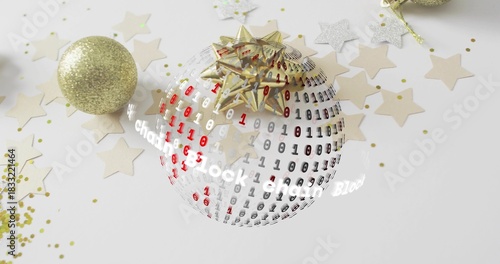 Showing orb wearing gold bow with binary digits on white tabletop, gold glitter balls and confetti
